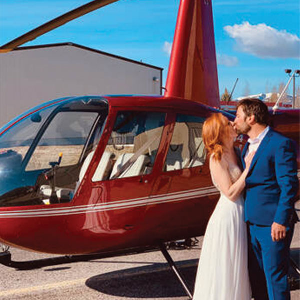 couple kissing in front of a helicopter